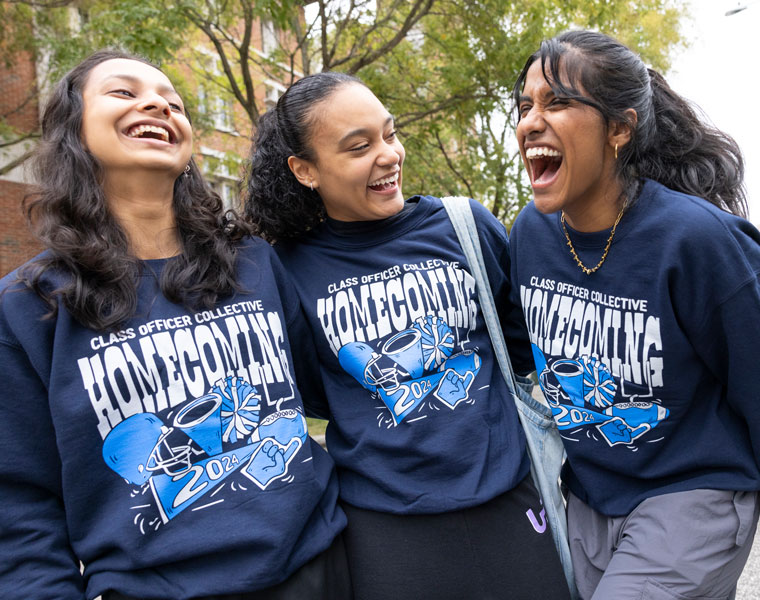 Photo of three smiling and laughing students posing for a photo during homecoming festivities