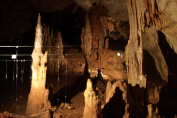 A large cavern with stalactites and stalagmites, artificially lit