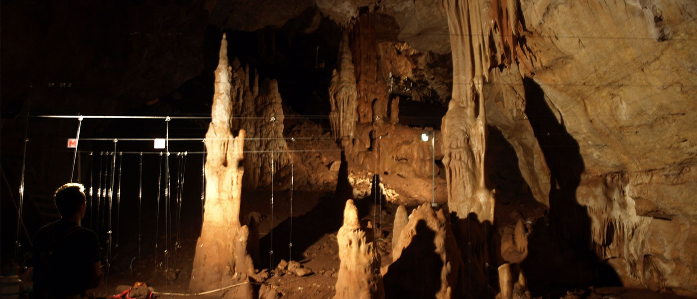 A large cavern with stalactites and stalagmites, artificially lit