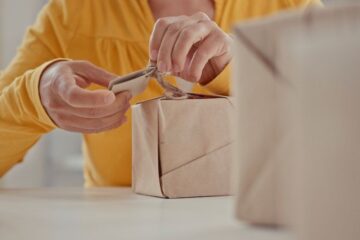 Woman dressed in yellow is wrapping gifts for her family with sustainable materials. Preparing for the holidays celebrations.