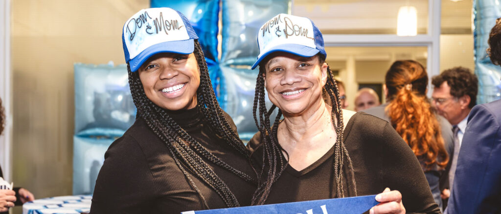 Photo of a staff member and her daughter with personalized hats and holding a CWRU pennant during the homecoming Blue Bash