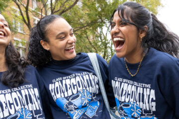 Photo of three smiling and laughing students posing for a photo during homecoming festivities