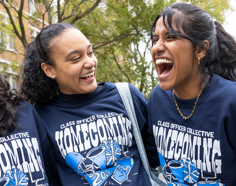 Photo of three smiling and laughing students posing for a photo during homecoming festivities