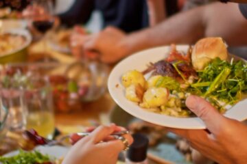 Close up of a man serving himself at a potluck dinner. Courtesy of Getty Images.