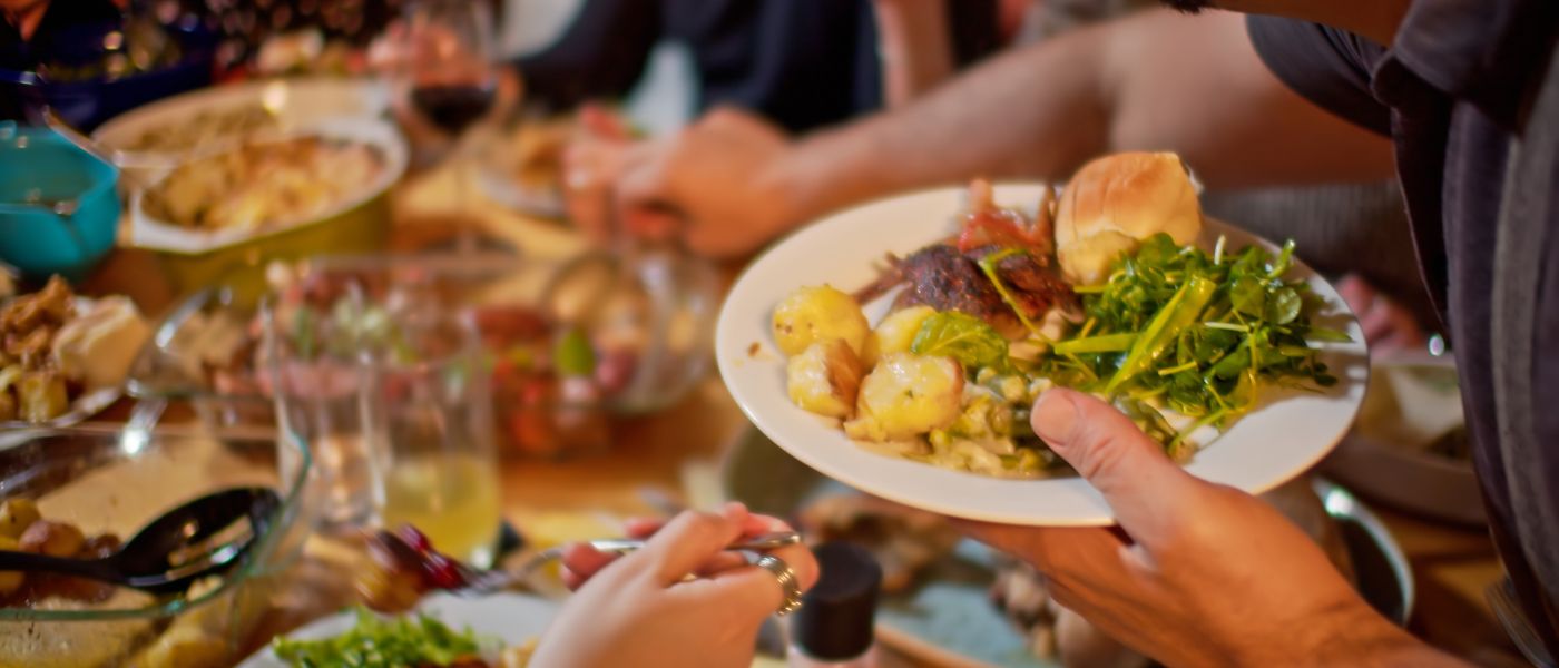 Close up of a man serving himself at a potluck dinner. Courtesy of Getty Images.