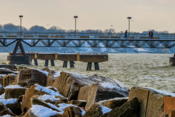 Photo of the pier at Edgewater with rocks covered in snow in the foreground