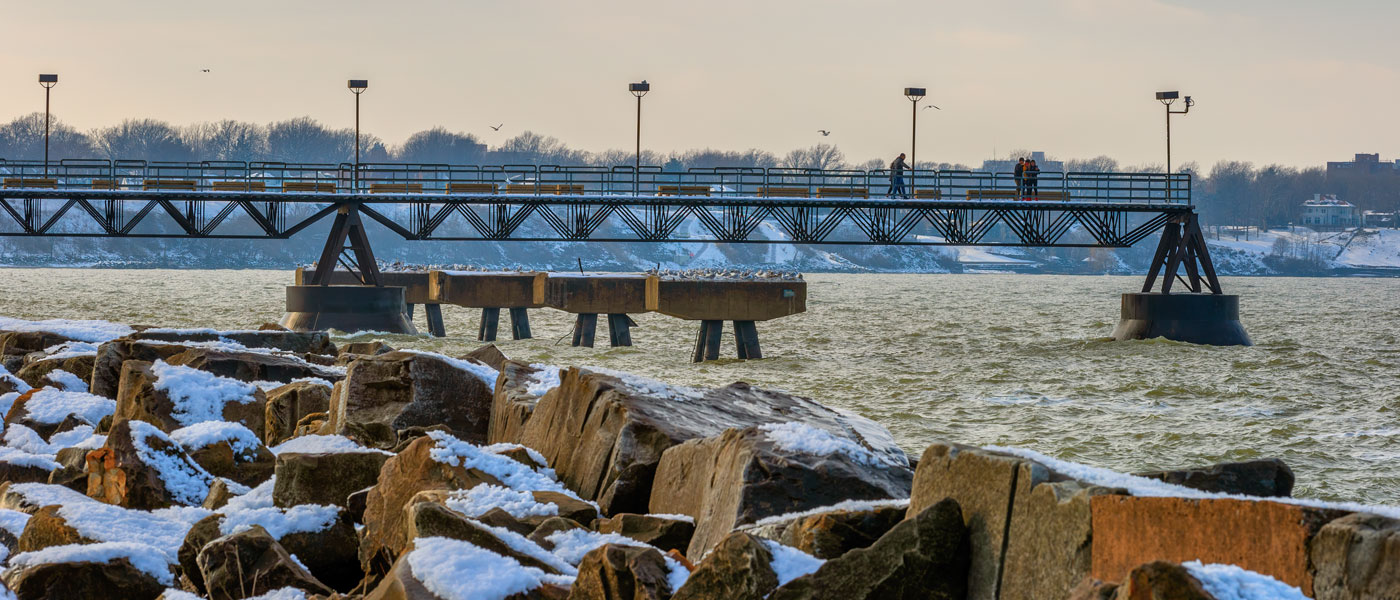 Photo of the pier at Edgewater with rocks covered in snow in the foreground