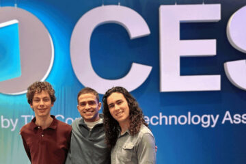 Photo of three CWRU students posing for a photo in front of CES signage