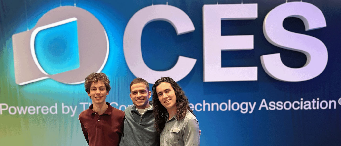 Photo of three CWRU students posing for a photo in front of CES signage