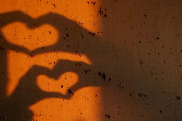 Shadow on the wall of heart shape made of hands, courtesy of Getty Images.